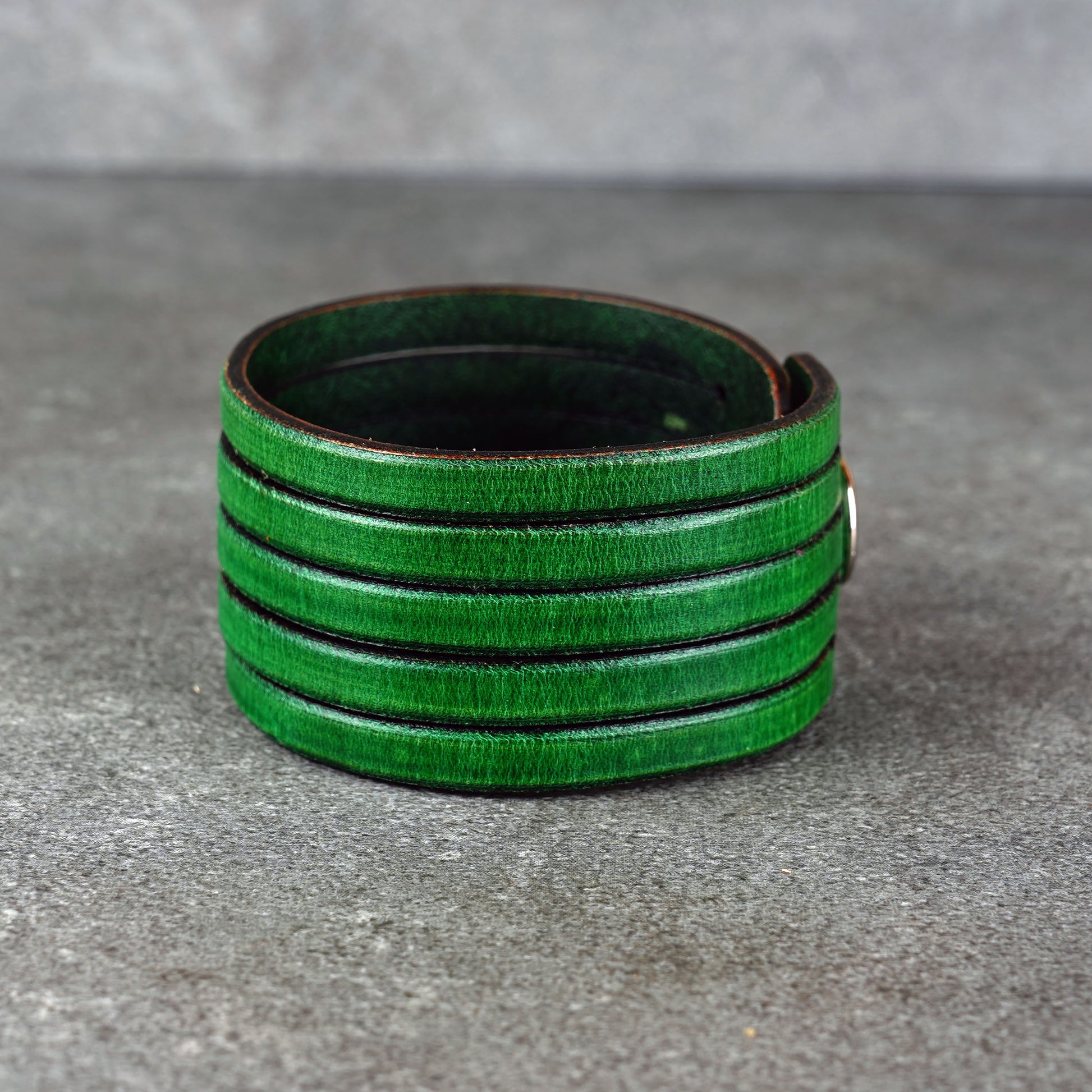 Green leather wrap bracelet on gray background, handmade genuine leather cuff bracelet with layered design, minimalist green wristband accessory for men and women
