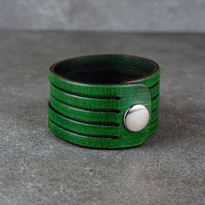 Green leather wrap bracelet on gray background, handmade genuine leather cuff bracelet with layered design, minimalist green wristband accessory for men and women
