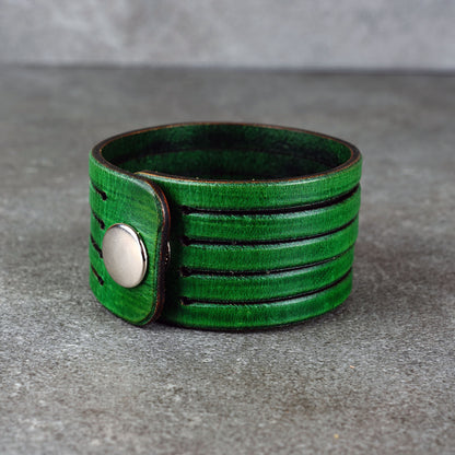 Green leather wrap bracelet on gray background, handmade genuine leather cuff bracelet with layered design, minimalist green wristband accessory for men and women
