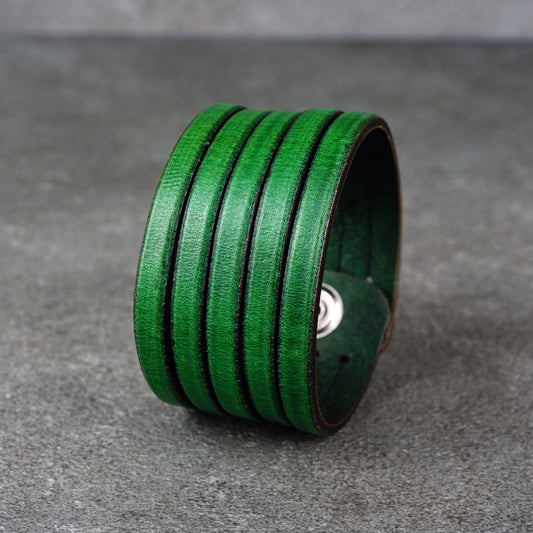 Green leather wrap bracelet on gray background, handmade genuine leather cuff bracelet with layered design, minimalist green wristband accessory for men and women
