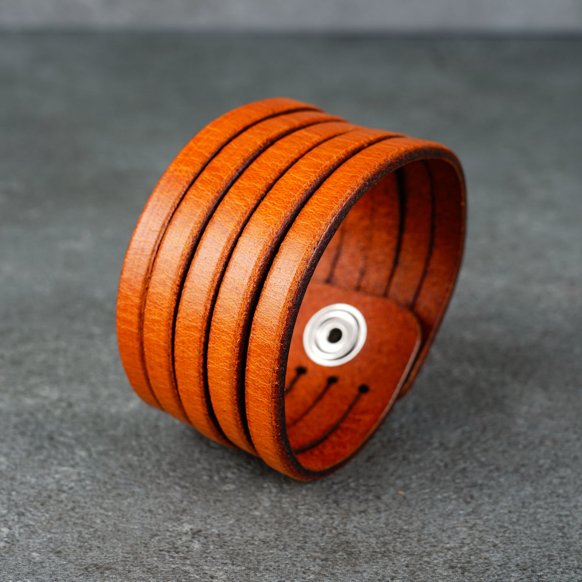 Angled view of the cuff showing the inner snap hardware and layered leather bands