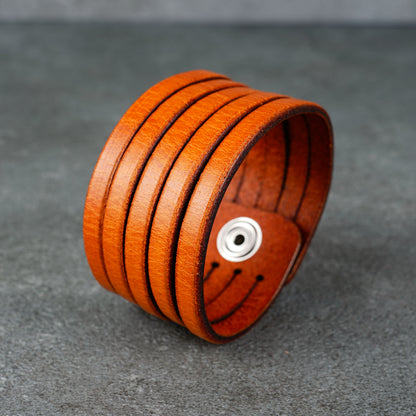 Angled view of the cuff showing the inner snap hardware and layered leather bands