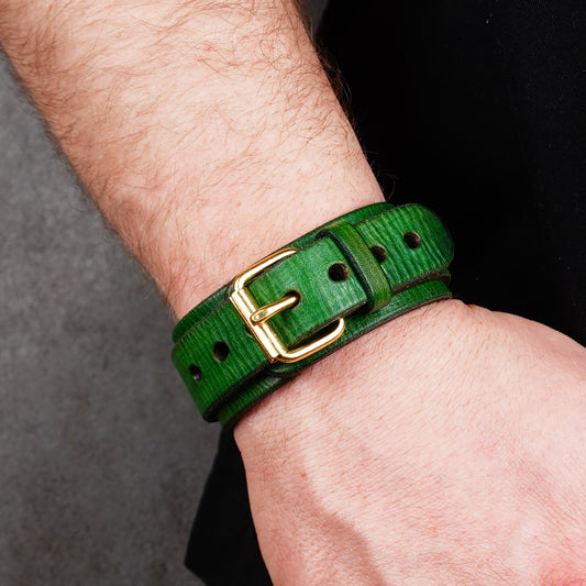 Green leather cuff bracelet worn on a wrist, showing the buckle and punched holes