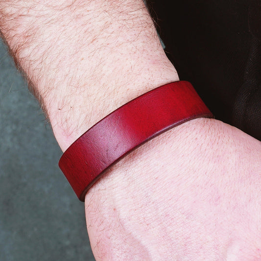Red leather cuff bracelet worn on a wrist, showing the wide band from above