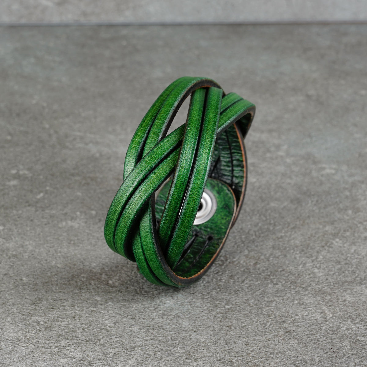 Green leather cuff standing upright on a gray surface