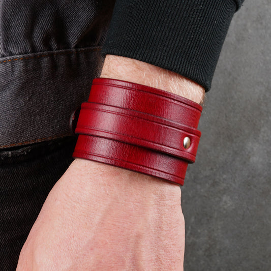 Red leather cuff bracelet on a wrist, close-up side view with a visible metal snap.