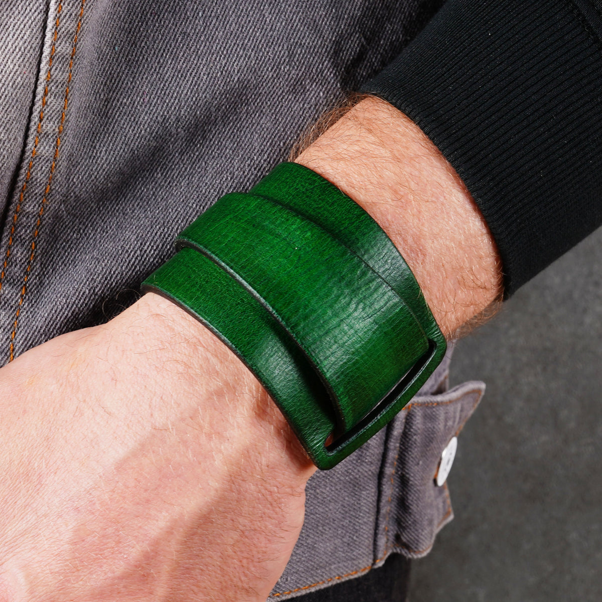 Green leather cuff bracelet worn across the wrist at an angle