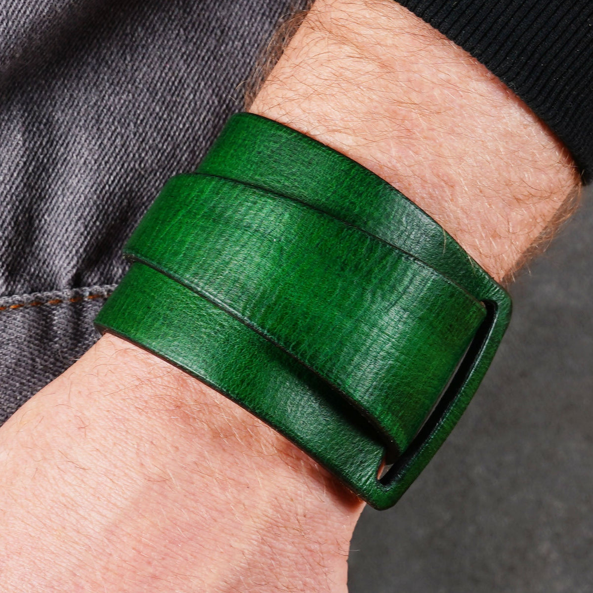 Green leather cuff bracelet worn on a wrist with a close side view