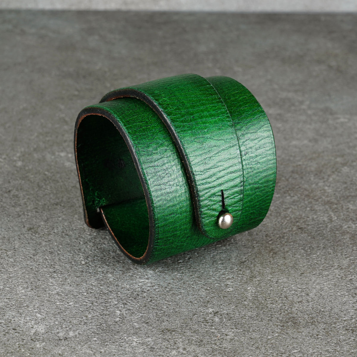 Green leather cuff bracelet angled to show the open end and layered profile