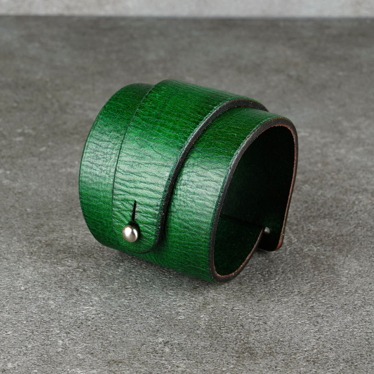 Green leather bracelet with a visible snap fastener shown against a gray background
