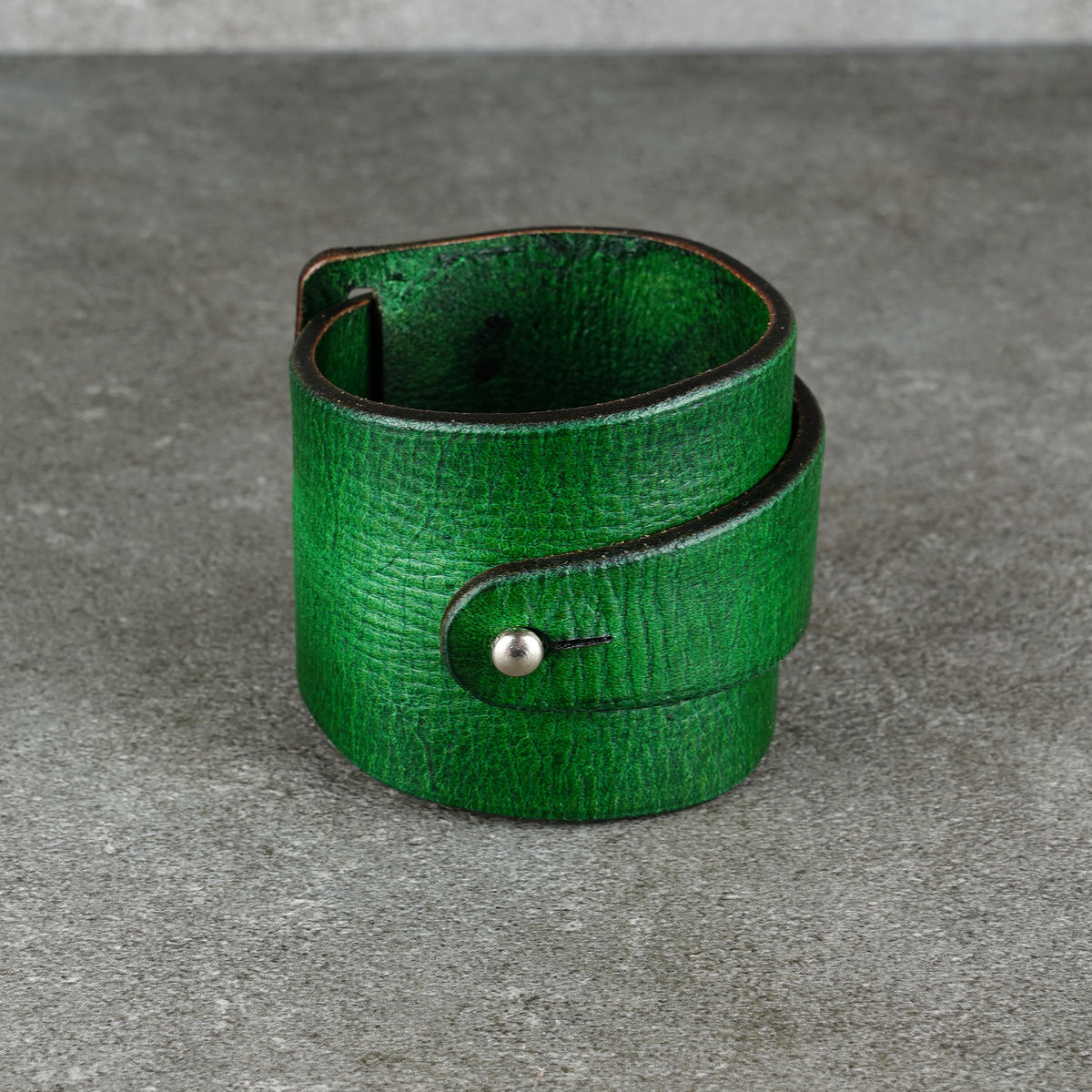 Front view of a green leather cuff bracelet with a snap closure