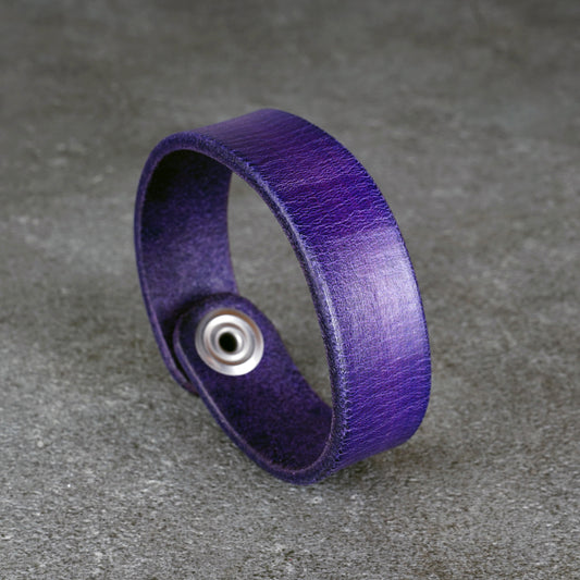 Close-up of the purple leather band and steel snap button on a gray background