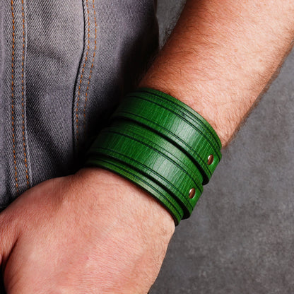 Green leather cuff bracelet shown from above on a wrist beside denim