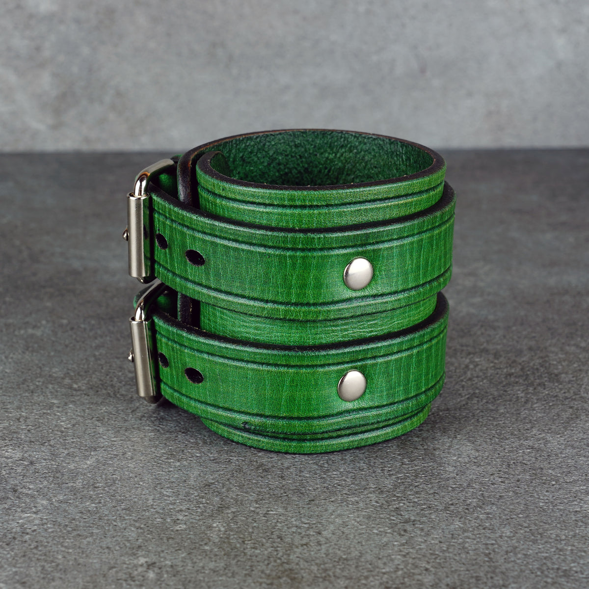 Green leather cuff bracelet with visible rivets and the fastening hardware in profile