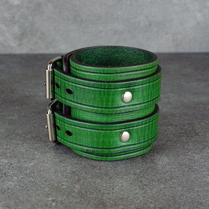 Green leather cuff bracelet with visible rivets and the fastening hardware in profile