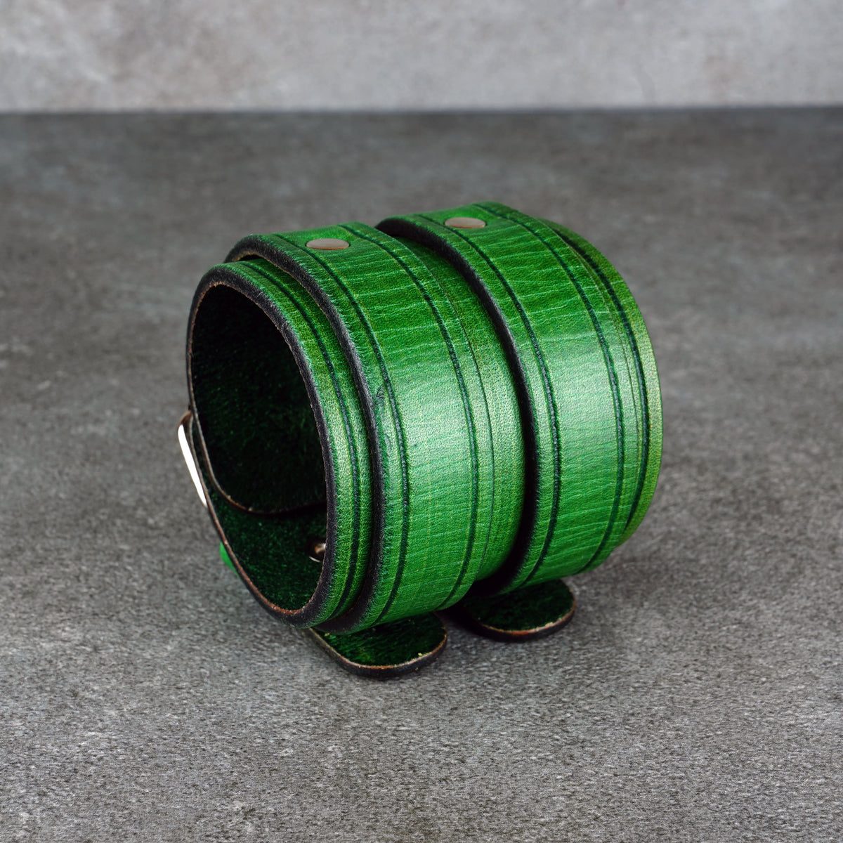 Green leather cuff bracelet lying open with the darker edge finish visible