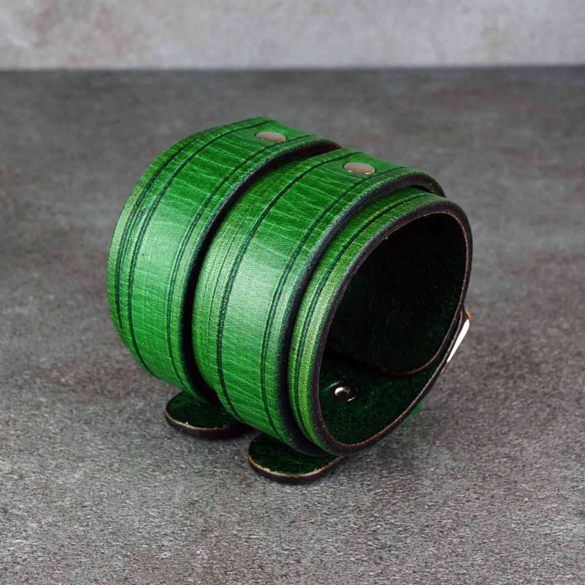 Close angled studio view of the green cuff bracelet showing the top grain and rivets